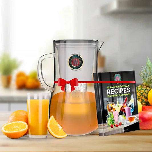 Juicer with orange juice and a book on alkaline beverage recipes on a kitchen counter.
