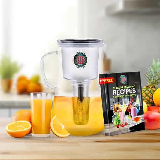 Juicer with orange juice and a book on alkaline beverage recipes on a kitchen counter.