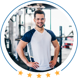 Man in a gym wearing a white and blue t-shirt with a blurred background